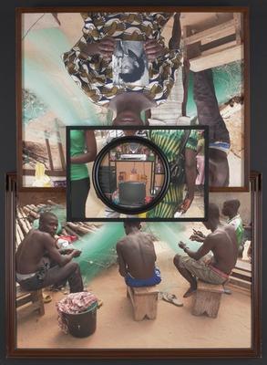 four separate colored photographs layered over each other and attached with black tape on the back; bottom photograph depicts four boys, seated, weaving a fishing net; boy on left turns to look at viewer; brown frame with beaded inner edging; top photograph image of figure in a patterned dress, holding a black and white portrait with both hands; face is obstructed by another photograph layered on top of the image; two figures stand behind front figure, with cascading fishing nets in the background; brown frame; center photograph depicts the torsos of three figures, right figure wearing a green and yellow tie dyed dress, holding a black purse; center figure wearing a white striped patterned button up shirt with matching pants; left figure wearing a green cotton shirt with black bottoms; image obstructed by center photograph overlapping; center photograph is round in shape, with an interior view of a televisions surrounded by electronic equipment on shelving; stuffed bears rest on shelves around television; rectangular gold trophy/ award rests on top of the television; cleat taped to back of installation